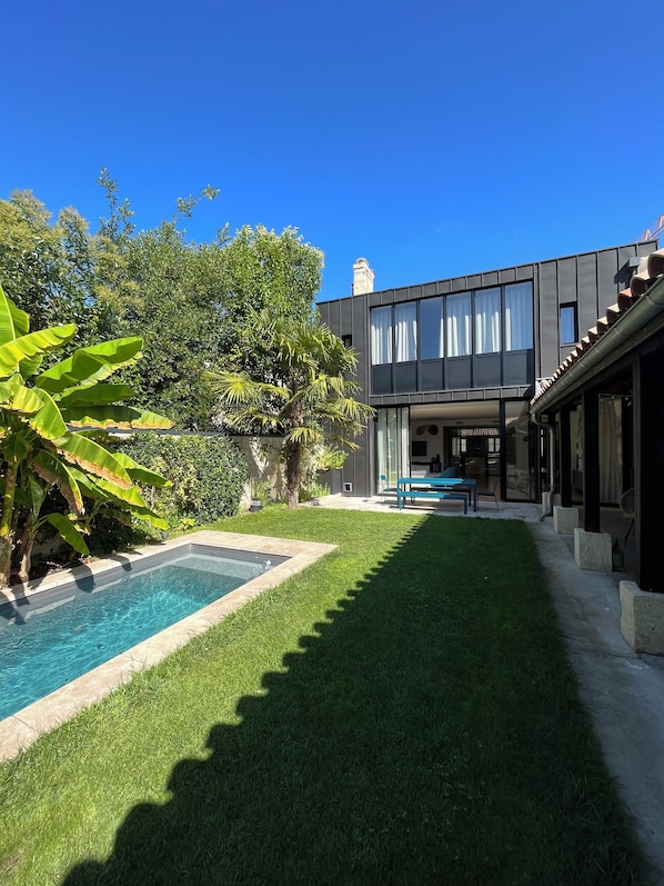 Uma casa moderna com piscina, gramado bem cuidado e área de varanda.