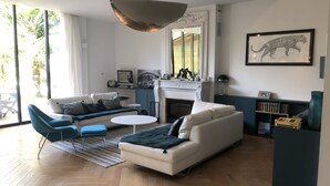 Ein modernes Wohnzimmer mit einer Couch, Sesseln, einem Kamin und einem Bücherregal.