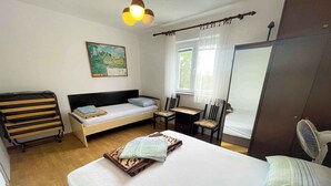 A bedroom with a bed, a desk, a chair, a wardrobe, and a window. - Holiday apartment with air conditioning (Jadranovo)