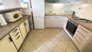 A compact kitchen with a microwave, refrigerator, sink, stove, and cabinets. - Holiday apartment with air conditioning (Jadranovo)