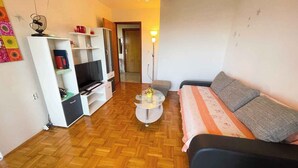 Een woonkamer met een bank, televisie, wit tv-meubel en een salontafel.