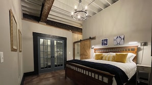 Een slaapkamer met een houten bed, een schuifdeurkast, een kroonluchter en een nachtkastje.