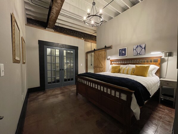 Un dormitorio con cama de madera, armario con puerta corredera estilo granero, candelabro y mesita de noche.