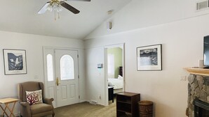 Ein Wohnzimmer mit Kamin, Deckenventilator und einer Tür mit Buntglasfenster.