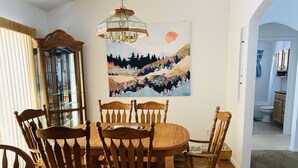 Ein Esszimmer mit Holztisch und Stühlen, einer Chandelieber und einem Gemälde einer Berglandschaft.