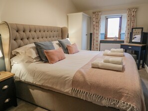 A neatly made bed with a tufted headboard, multiple pillows, and a folded blanket. - Coppa Hill Barn (Carnforth)