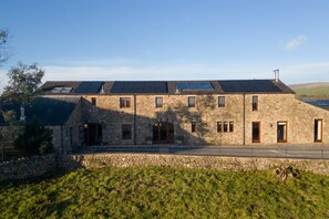 A stone building with multiple windows and a sloped roof. - Coppa Hill Barn (Carnforth)