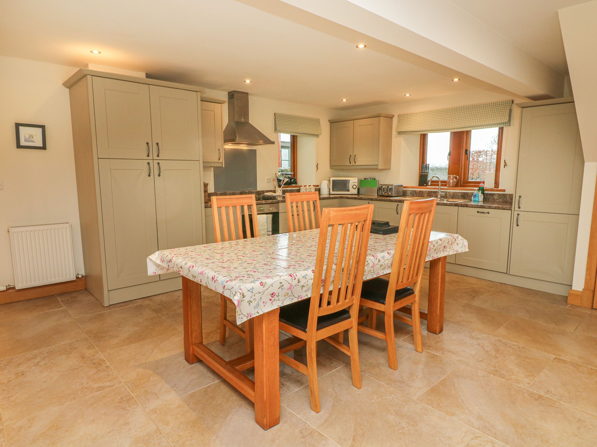 A modern kitchen with a dining table, chairs, and a range hood.