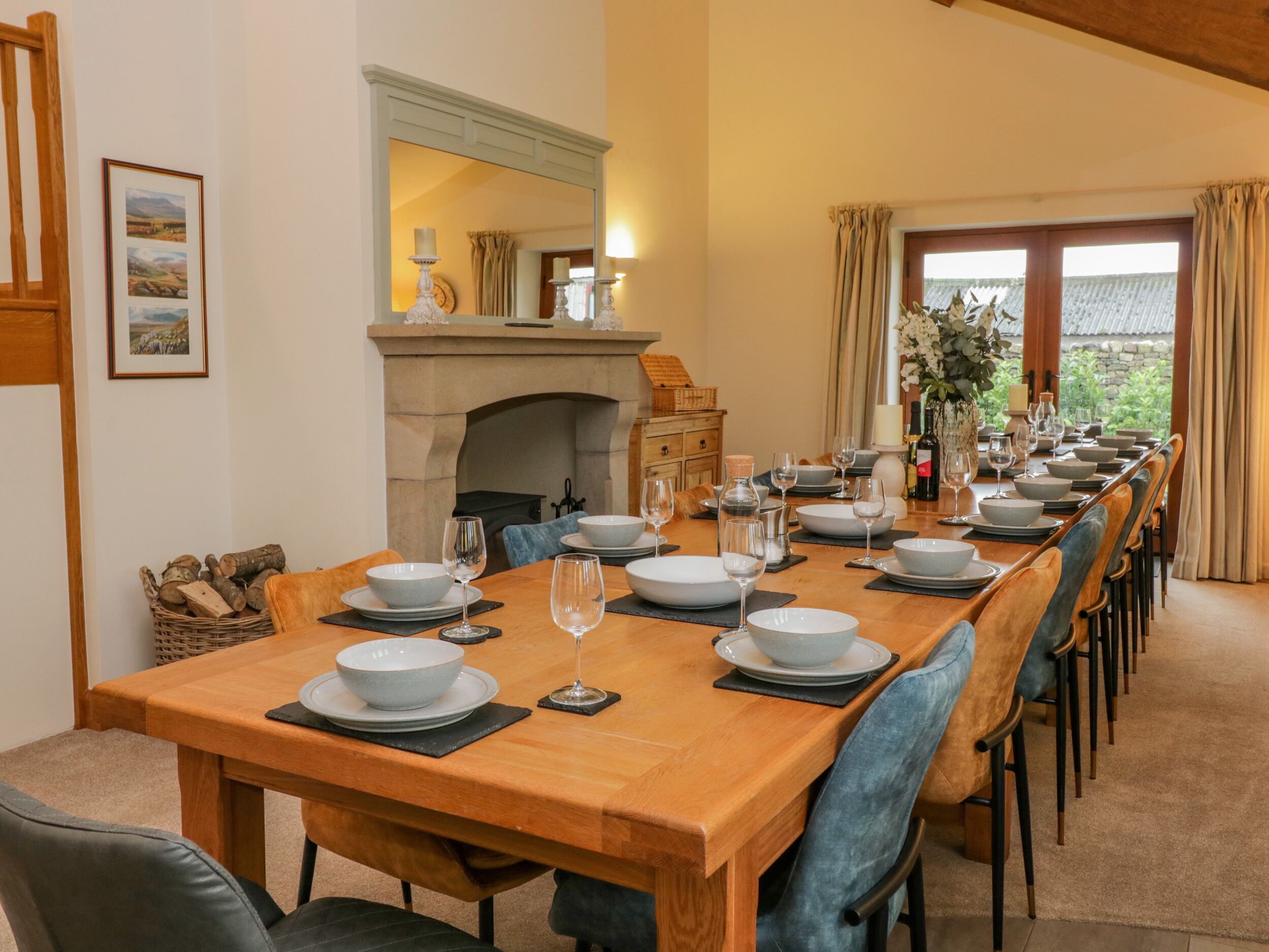 A dining area with a long wooden table set for a meal, flanked by chairs with blue upholstery.