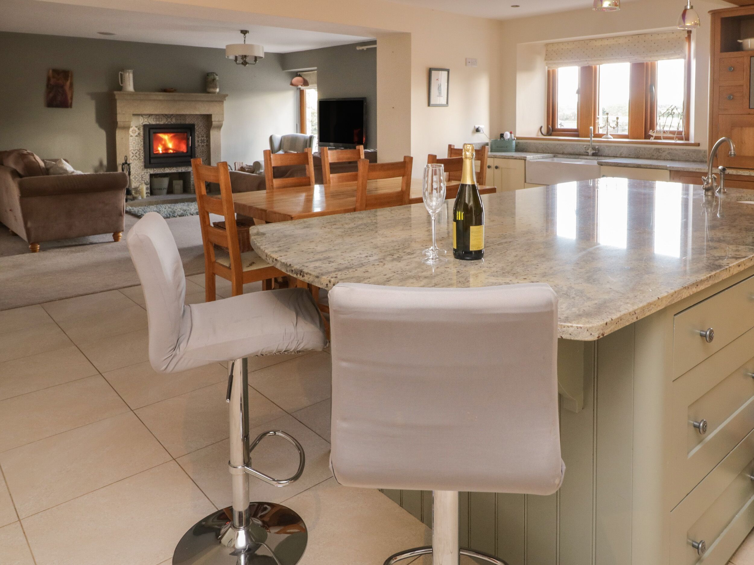 A kitchen with a marble countertop, a wine bottle, and a TV.