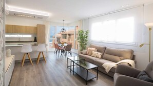 A modern living room with a sofa, coffee table, and dining area with chairs. - Deluxe Beach Canteras Flat 3br Wifi Free 1ºA (Palmas De Gran Canaria, Las)