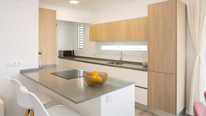 A modern kitchen with a central island, white cabinetry, and a window providing natural light. - Deluxe Beach Canteras Flat 3br Wifi Free 1ºA (Palmas De Gran Canaria, Las)