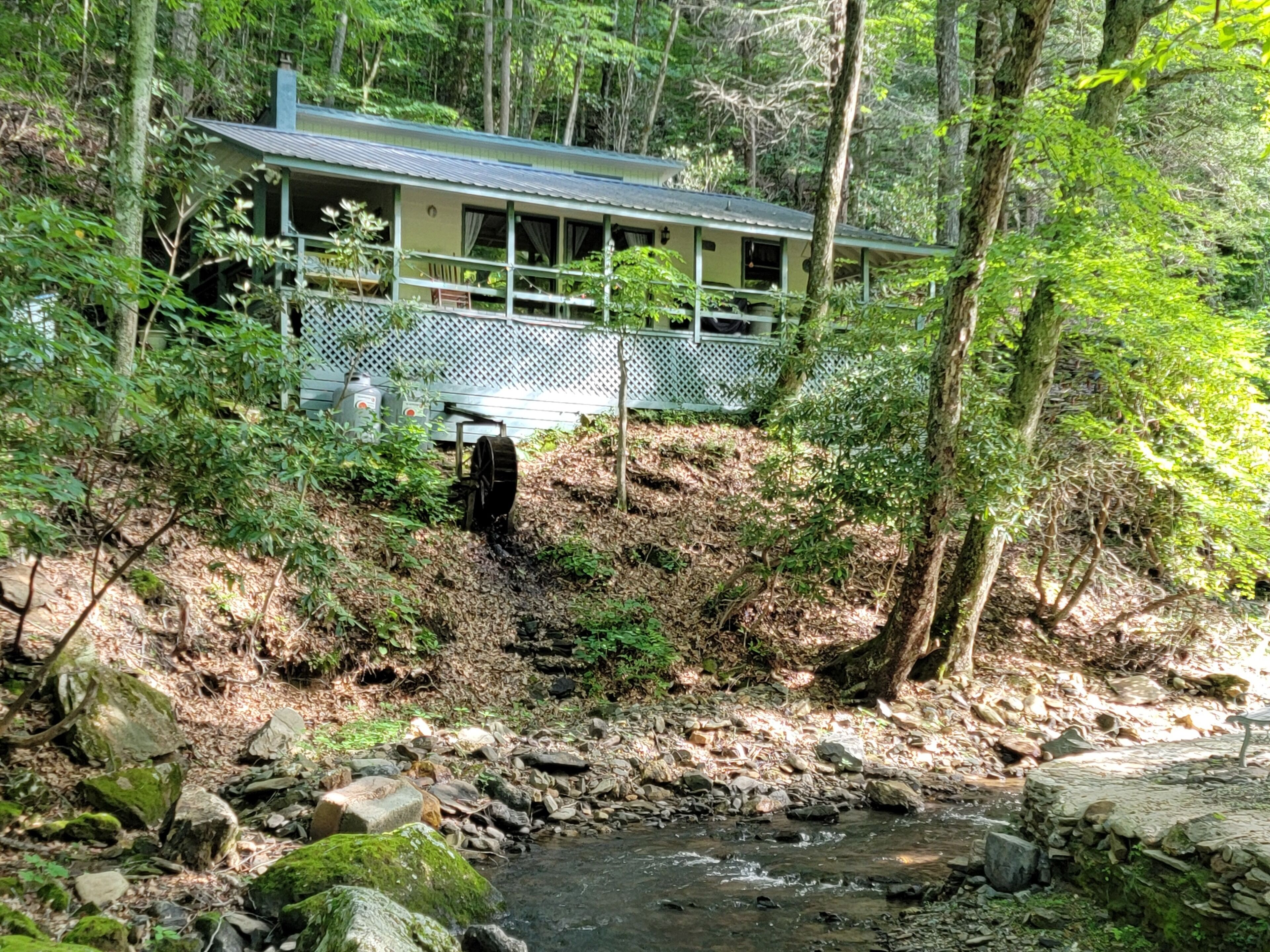 Un chalet rustique doté d’une véranda, entouré d’une forêt dense.