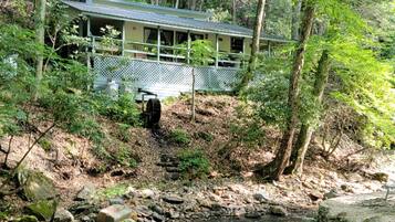 Un chalet rustique doté d’une véranda, entouré d’une forêt dense.