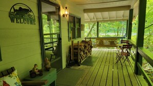 Une véranda en bois avec un banc, une table et une pancarte de bienvenue.