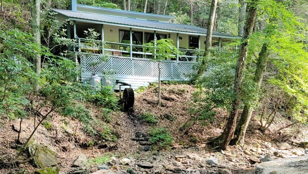 Une cabane dotée d’une véranda et offrant une vue sur une zone boisée.