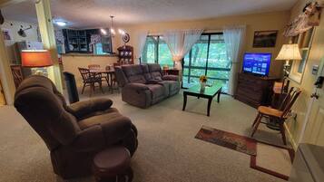Un salon comprenant un canapé, un fauteuil, une table à manger et un téléviseur.