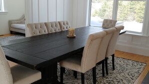 Un comedor con una mesa de madera oscura, sillas blancas tapizadas y un banco.