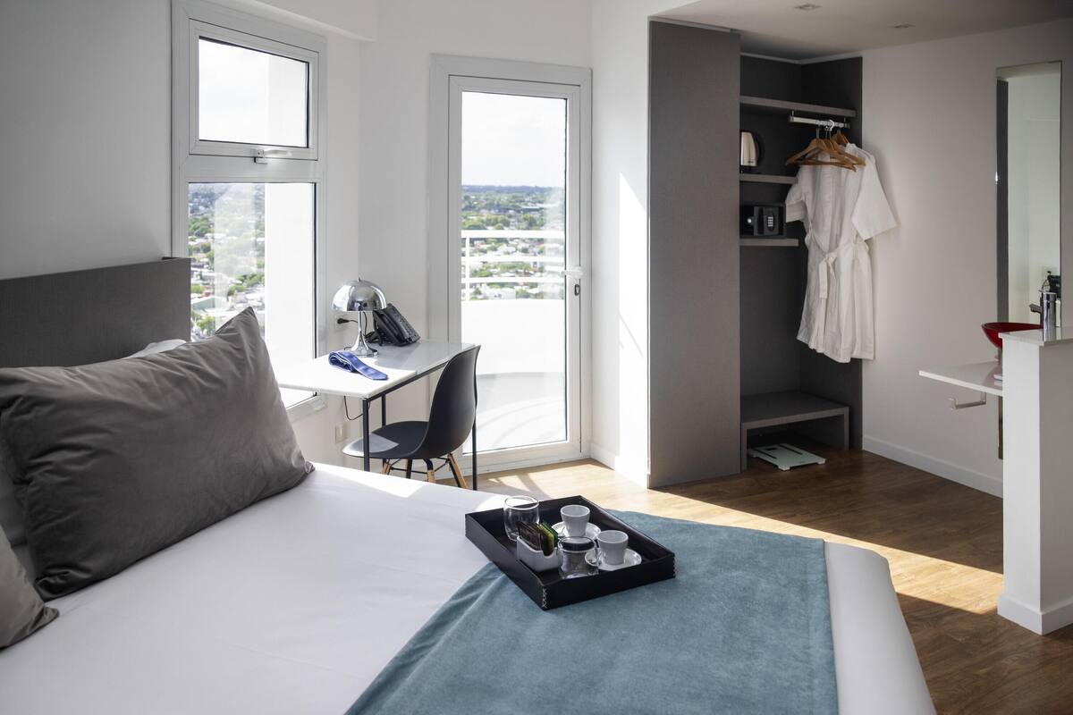 Een moderne hotelkamer met een bed, een bureau, een stoel en een balkon met uitzicht.