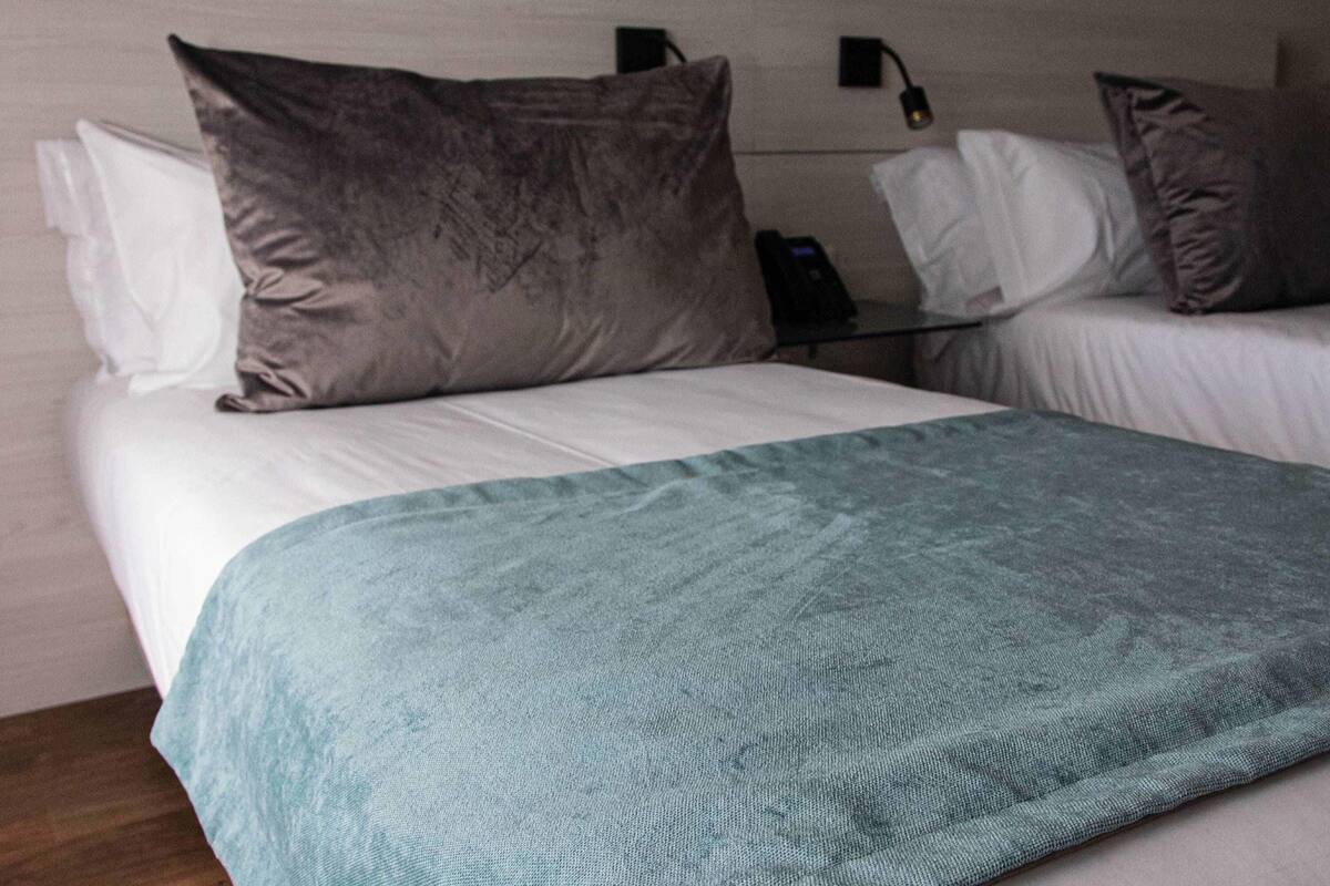 Een hotelkamer met twee bedden, elk voorzien van een kussen en een dekbed.
