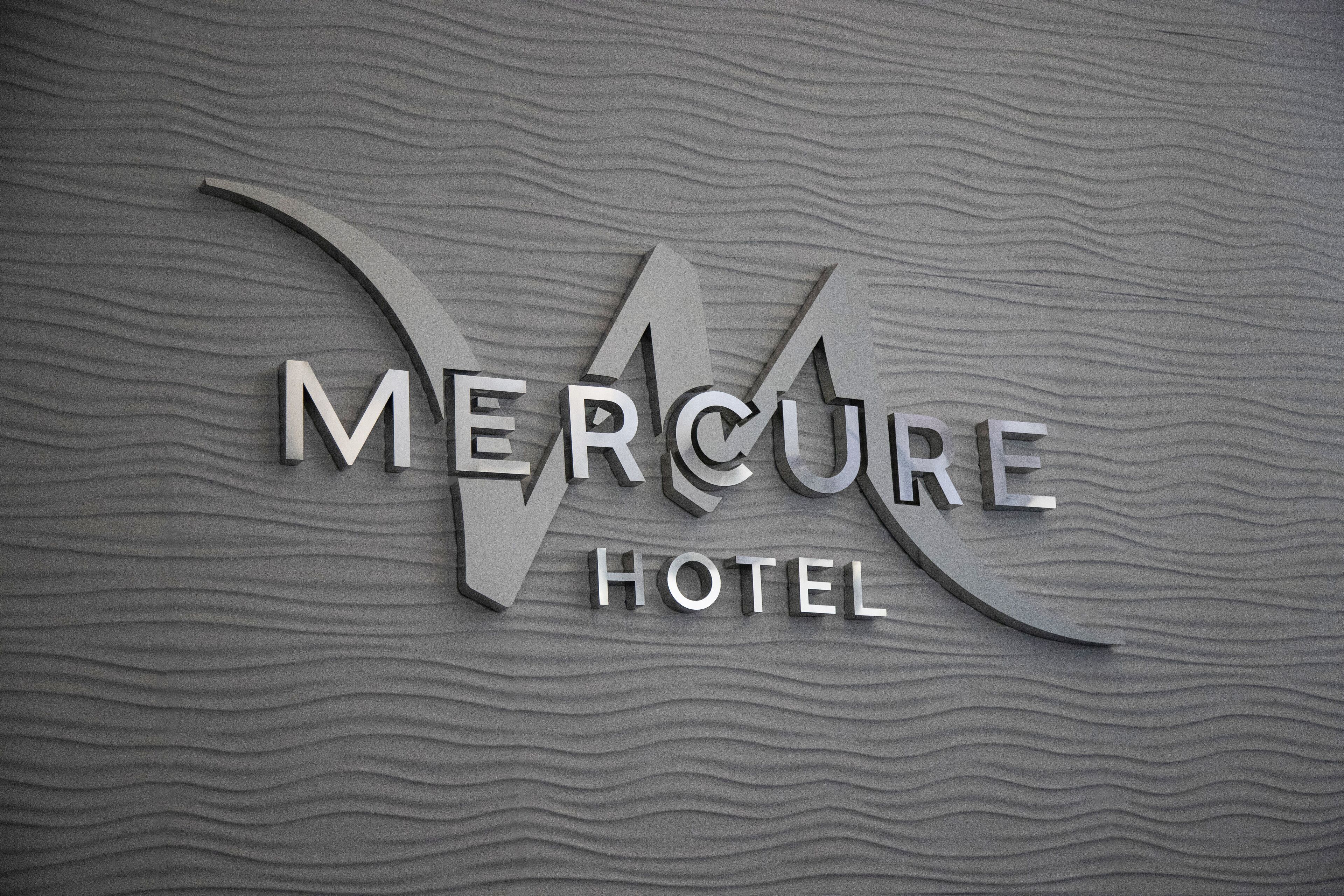 Un letrero de hotel en 3D con el nombre 'Mercure Hotel' sobre una pared texturizada.