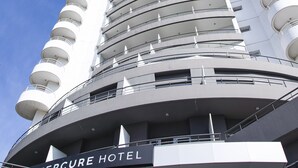 A tall, modern hotel with a curved facade and multiple balconies.