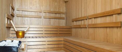 Una sauna de madera con bancos y un cubo.