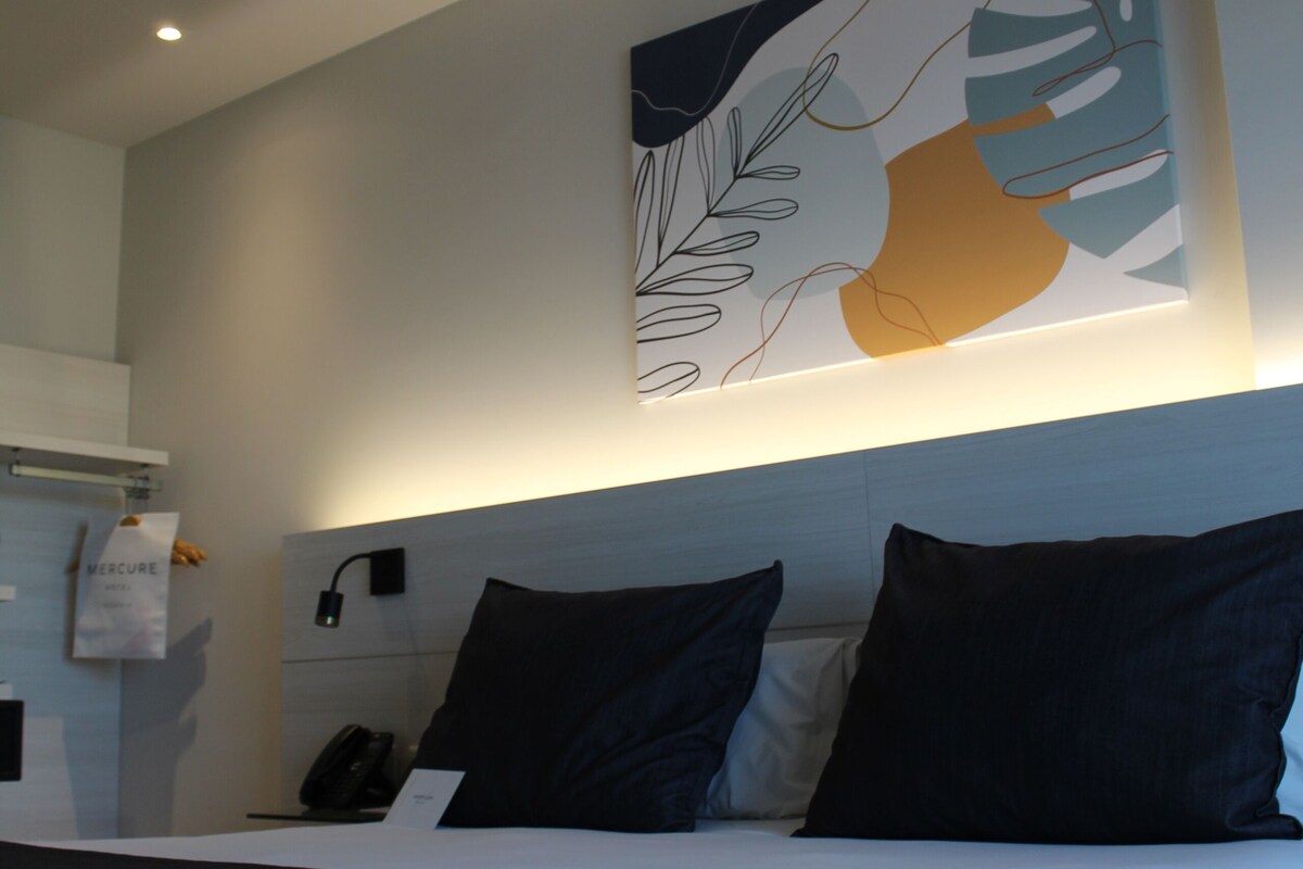 Een hotelkamer met een bed, een bureau en een aan de muur bevestigd telefoontoestel.