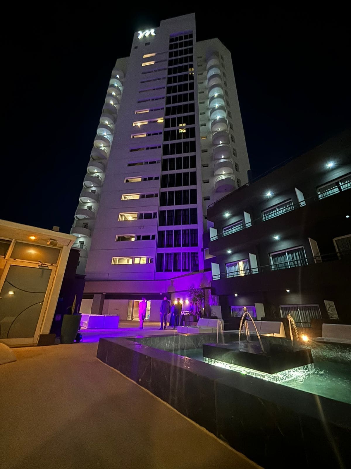 Un grand hôtel à plusieurs étages, doté d’une piscine et d’un hall d’entrée bien éclairé.