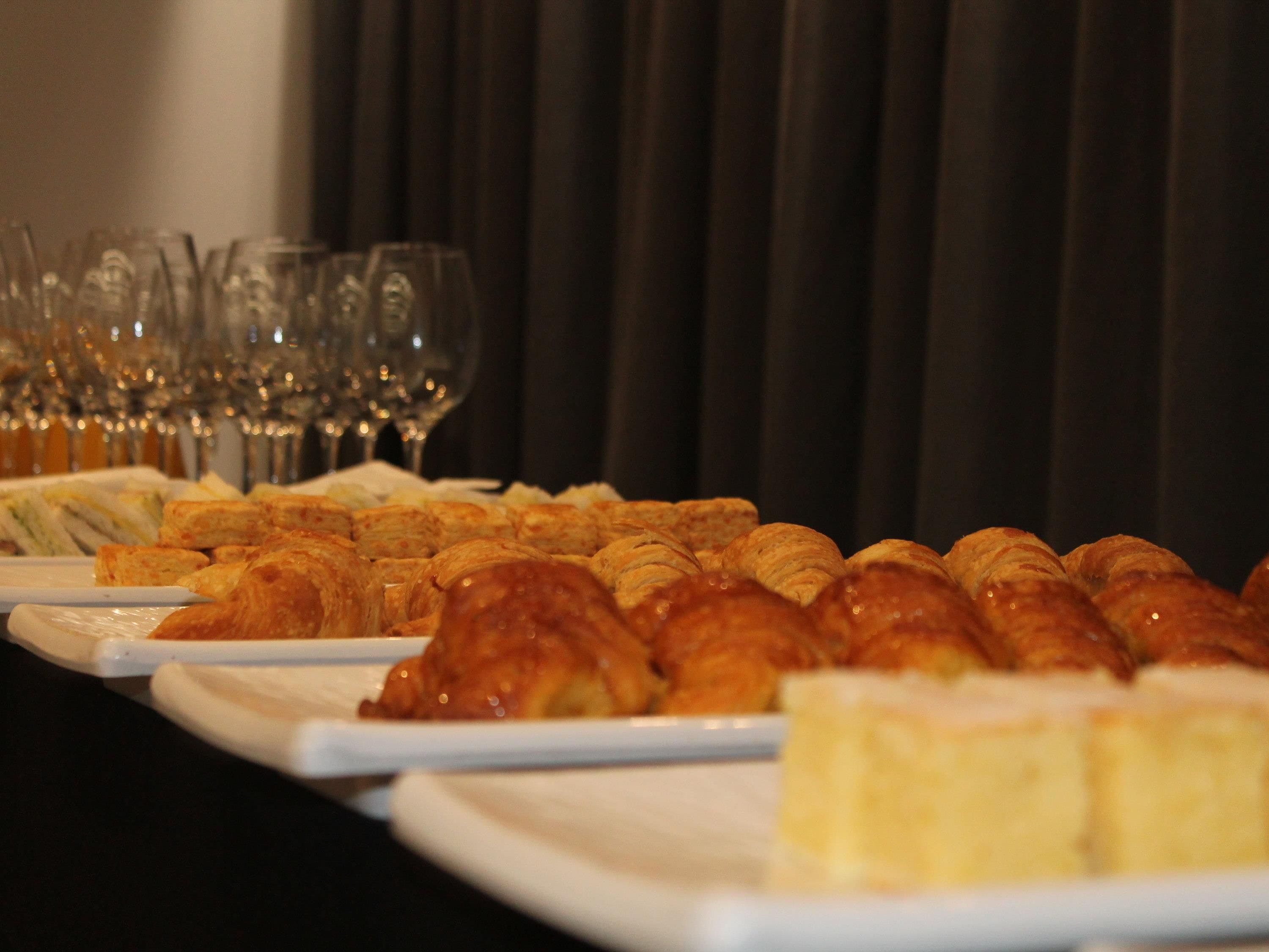 Uma mesa de buffet com doces e copos de vinho.
