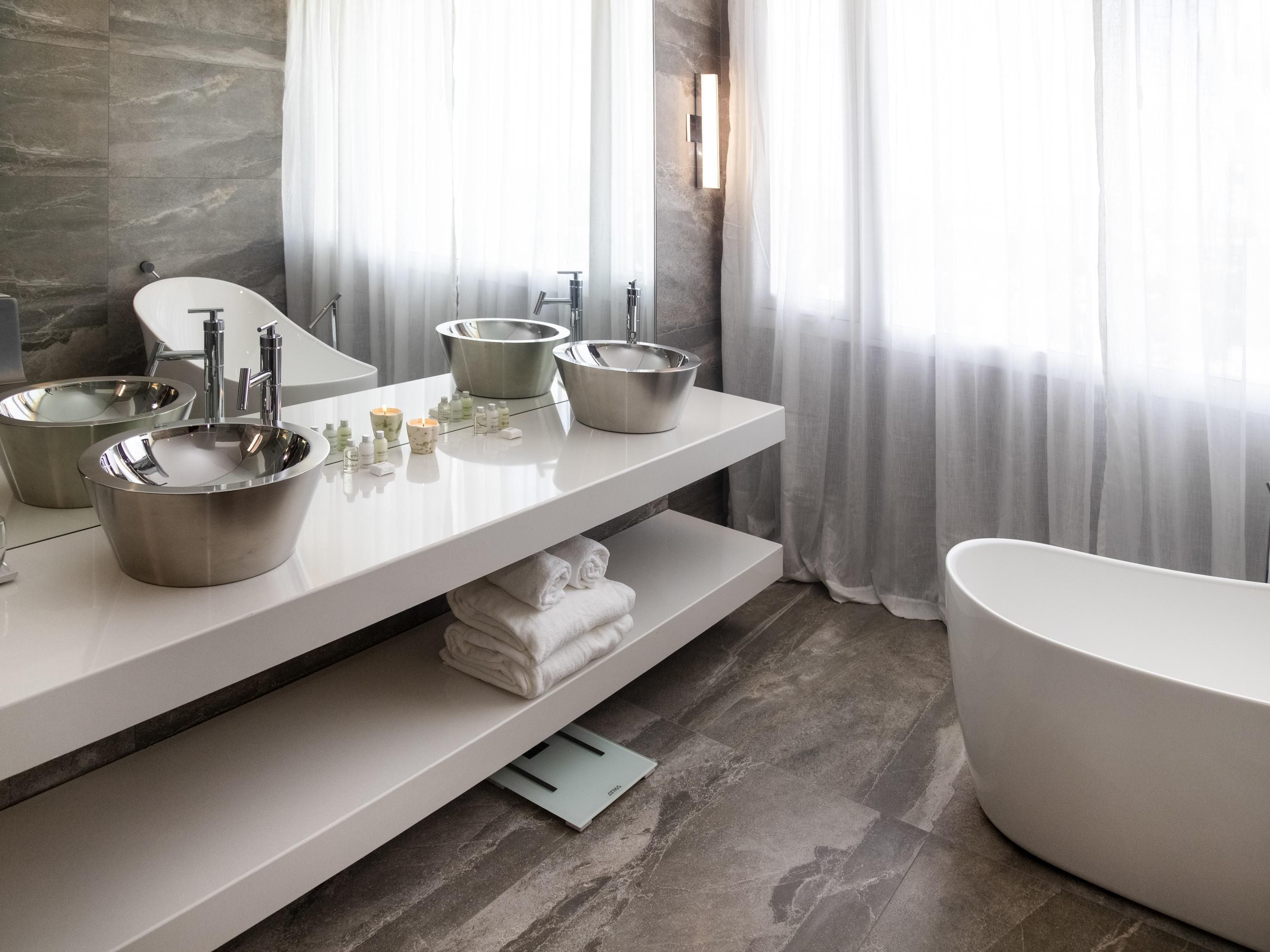 Ein modernes Badezimmer mit zwei Waschbecken, einer großzügigen Badewanne und einem Handtuchhalter.
