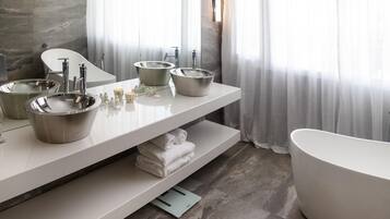 Un baño moderno con dos lavamanos, una bañera grande y un perchero para toallas.