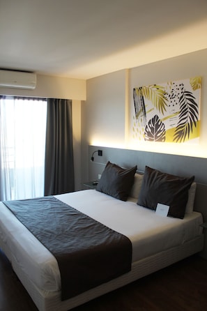 A modern hotel room with a large bed, a bedside table, a wall-mounted air conditioner, and a window with curtains. - Mercure Hotel Rosario (Rosario)