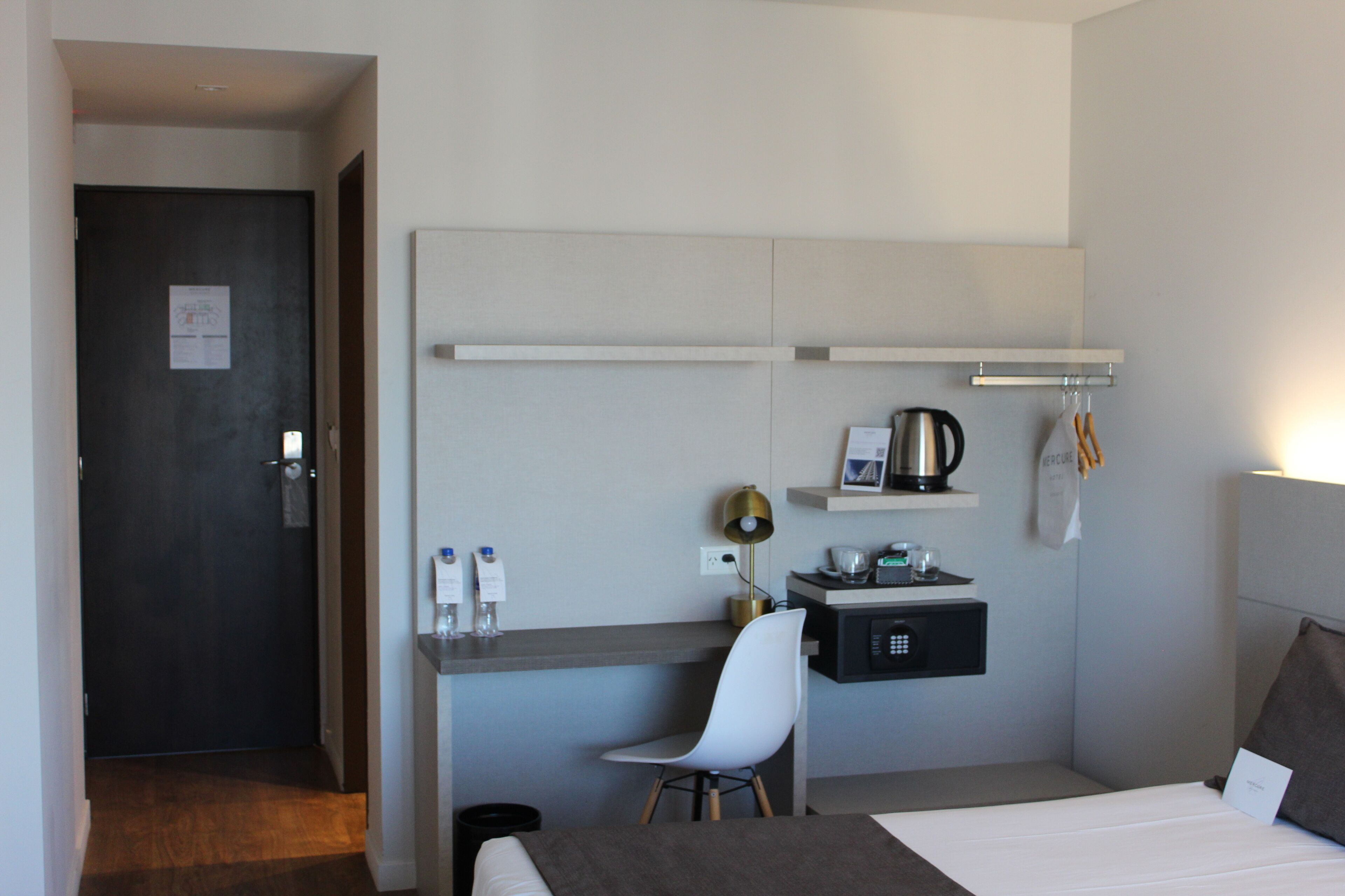 Una habitación de hotel moderna con una cama, un escritorio con silla, una pequeña kitchenette y acceso al baño.