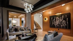 Ein modernes Wohnzimmer mit einer Chandelieber, einem großen abstrakten Gemälde und einer Treppe, die in eine andere Ebene führt.