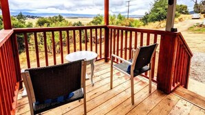 A wooden deck with a covered area, two chairs, and a small table.