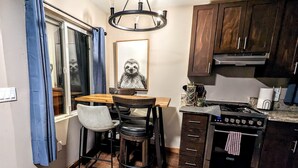 A compact kitchen with wooden cabinets, a gas stove, and a dining area with a table and chairs.