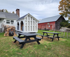 Enjoy outdoor dining and relaxation at this charming cabin retreat, featuring a rustic picnic area with two tables and benches.