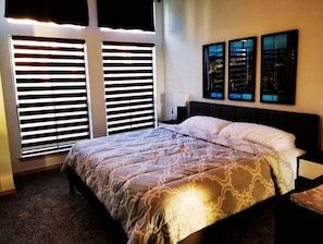 Relax in this inviting space with a large bed, two nightstands, and a window with blinds.