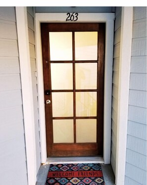 Welcome to a charming entrance with a traditional door featuring a glass panel and a doormat with a warm greeting.