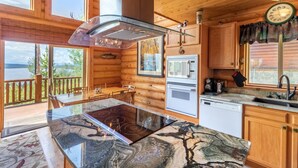 Una cabaña de troncos con cocina que incluye una isla de vidrio, horno empotrado y microondas.