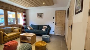 A cozy living room with a sofa, a coffee table, and a blue bean bag. - Le Refuge du Cabri -15 people- sauna - jacuzzi Les Ménuires -Skis aux Pieds (LES BELLEVILLE)