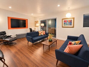 A modern living room with two sofas, a coffee table, and a TV mounted on the wall.