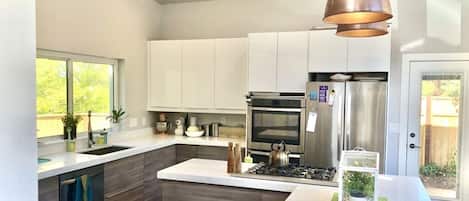 Een moderne keuken met witte kasten, roestvrijstalen apparatuur en een centraal eiland.