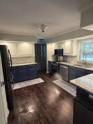 A modern kitchen with white cabinets, a black refrigerator, a microwave, and a dishwasher. - Stunning Lake Gaston waterfront! Renovated 3BR 2BA with dock on an acre lot. (Henrico)