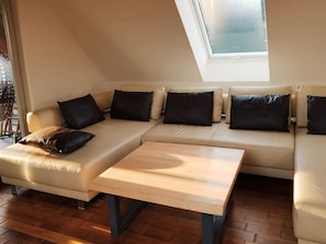 A modern living room with a sectional sofa, a coffee table, and a skylight. - Luxury apartment in downtown Erfurt (Erfurt)