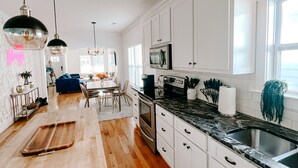 Une cuisine moderne avec des meubles blancs, un plan de travail en bois et un îlot central.