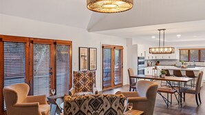 A modern kitchen with a central island, wooden blinds, and a dining area with chairs and a table. - Red Rock Awakening - Spacious Uptown home (Sedona)