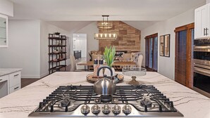 A modern kitchen with a central island, a built-in stove, and a dining area in the background. - Red Rock Awakening - Spacious Uptown home (Sedona)