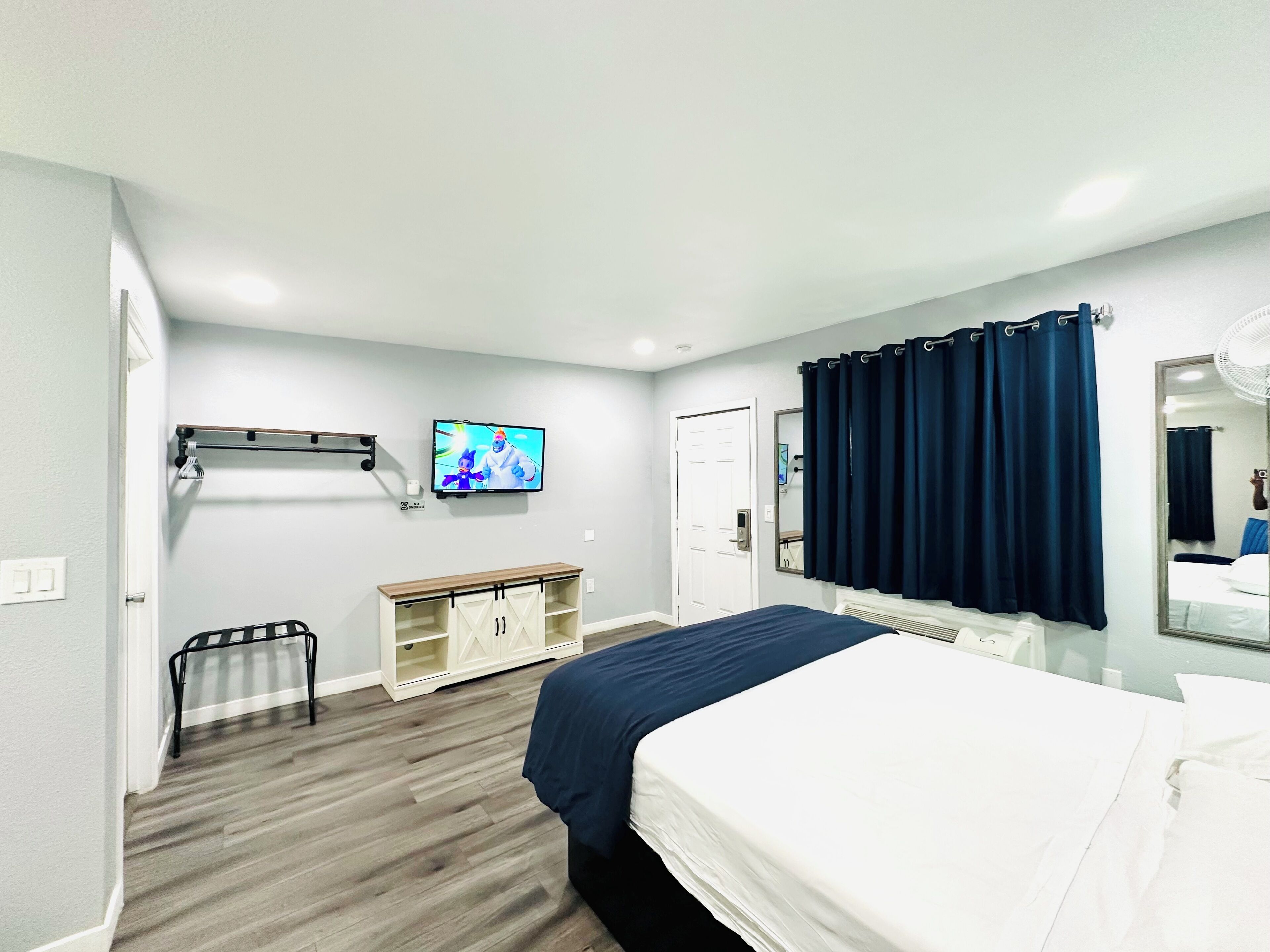 Een hotelkamer met een bed, een televisie, een kledingkast en een spiegel.